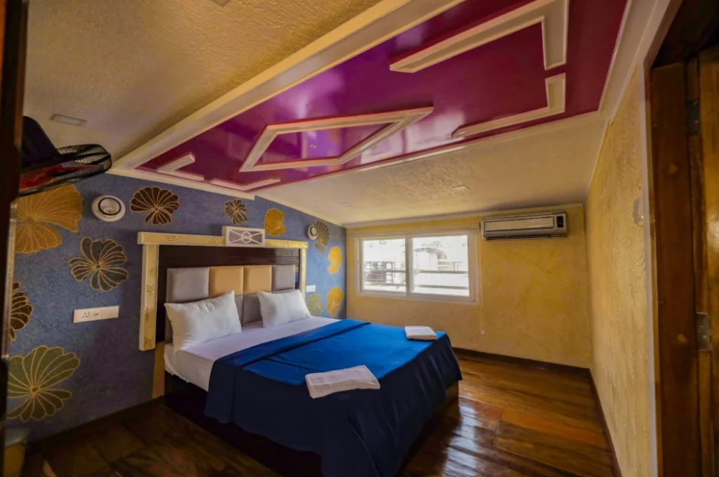 Premium bedroom suite with magenta decorative ceiling, botanical wall art, and water-facing window