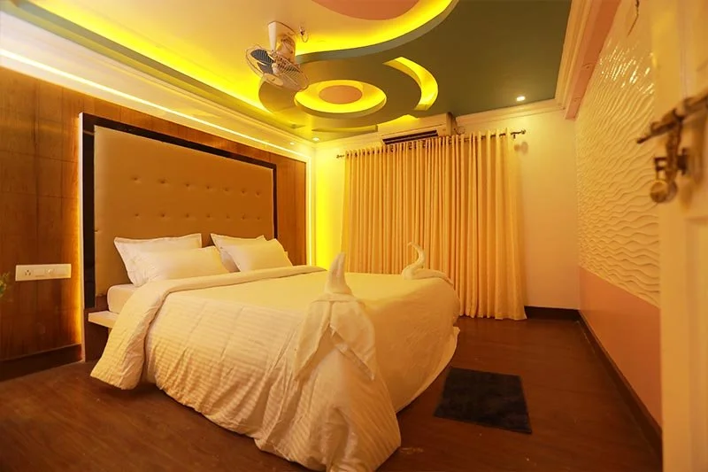 Royal AC stateroom with tufted headboard, curved circular pop ceiling, warm cove lighting, and elegant drapes